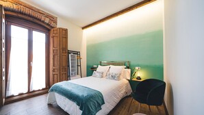 A bedroom with a bed, a chair, a nightstand, and a window with curtains. - Room 1 with double bed - La Dehesa (Urda)