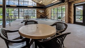 A spacious indoor area with a large table and chairs, a pool, and large windows offering views of the outside. - Good Vibes Only * Studio Condo for 2 wifi pool WFH (Gatlinburg)