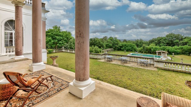 A covered patio with columns, outdoor furniture, and a view of a pool and garden. - Chateau de Pourpry (Damiatte)