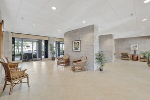 Relax in our spacious lobby, featuring a high ceiling, comfortable seating, and lush greenery.
