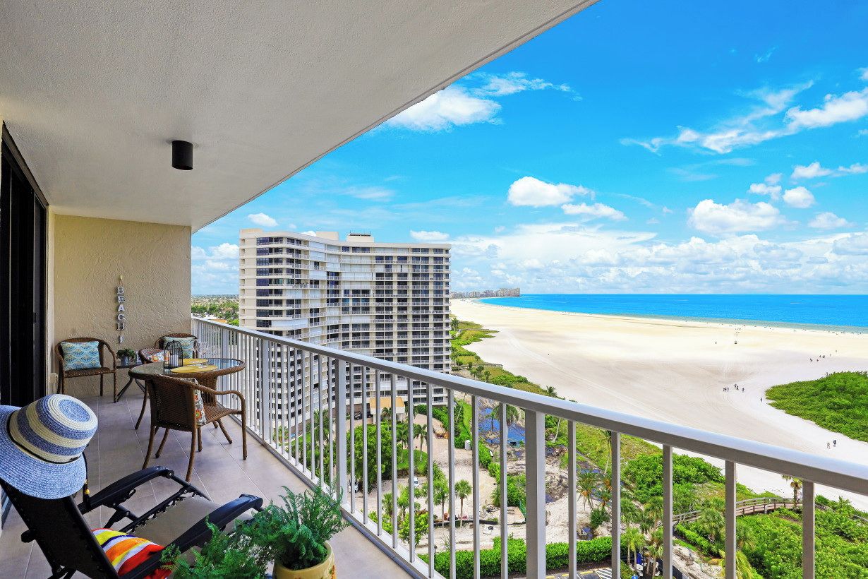A balcony with a view of a beach and a hotel building.
