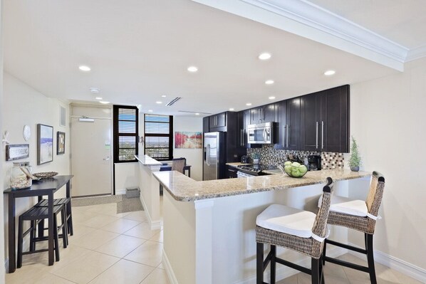 Enjoy cooking in this well-equipped kitchen with a granite countertop, stainless steel appliances, and a convenient island with seating.