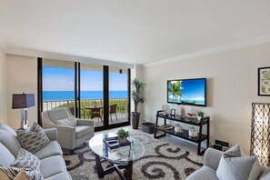 Enjoy the breathtaking ocean view from the comfort of this stylish living room, featuring a sofa set, flat-screen TV, and potted plant.