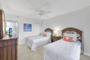 A hotel room with two beds, a ceiling fan, a dresser, and a painting on the wall. - Beachfront Condo | Views, Pools & Tennis Courts (Marco Island)