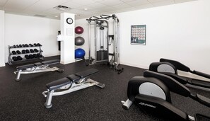 Un gimnàs amb cintes de córrer, aparells de musculació, peses i pilotes d'exercici.