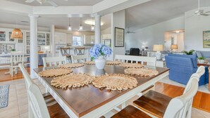 A spacious dining area with a large wooden table, white chairs, and a vase of flowers. - Lollipops Beach House - Four Bedroom, Three Bath, Private Pool in Long Bay (Myrtle Beach)