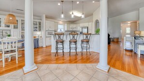 A spacious kitchen with white cabinetry, a central island with bar stools, and pendant lighting. - Lollipops Beach House - Four Bedroom, Three Bath, Private Pool in Long Bay (Myrtle Beach)