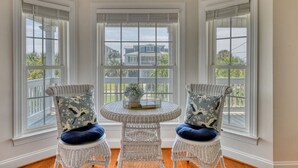 A corner room with three white wicker chairs, a round table, and large windows with blinds. - Lollipops Beach House - Four Bedroom, Three Bath, Private Pool in Long Bay (Myrtle Beach)