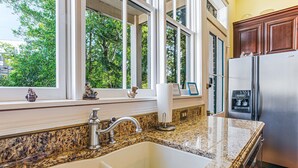 Una cocina con encimera de granito, electrodomésticos de acero inoxidable y una ventana con vistas a árboles.