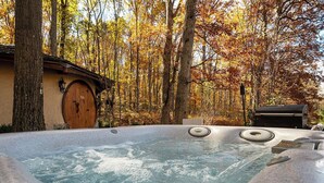 Ein Whirlpool in einer bewaldeten Gegend, im Hintergrund ein rustikales Gebäude.