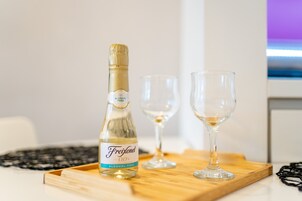 Una botella de champán Freixenet sobre una bandeja de madera con dos copas de vino vacías.
