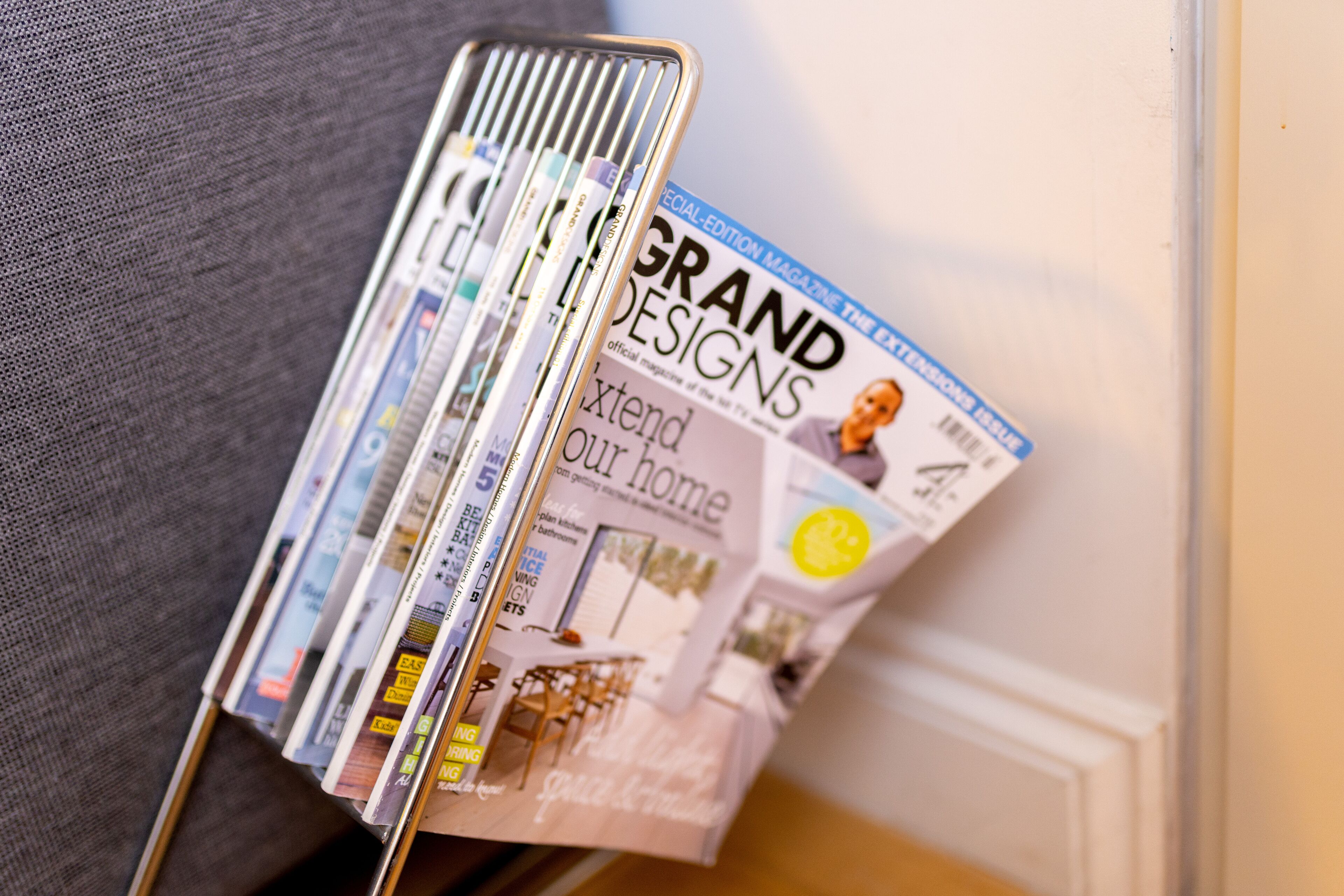 A magazine rack with various magazines, including one titled "Grand Designs."