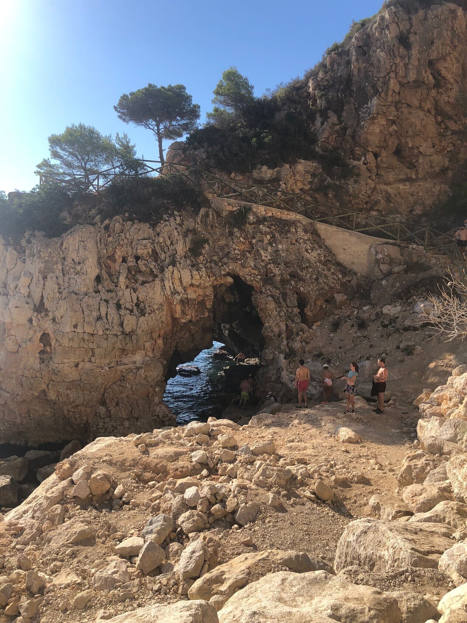 A rocky coastal area with a cave entrance and a wooden staircase leading up.
