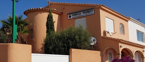 A building with a pharmacy sign, a white garage door, and a satellite dish.