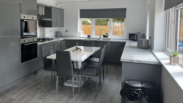 A modern kitchen with a central island, built-in appliances, and a large window providing natural light.