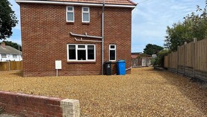 A brick house with two windows, a garage door, and a pile of dry leaves in the yard.
