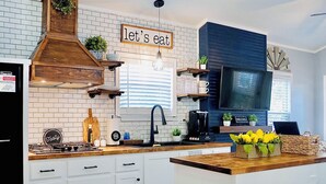 Una cocina moderna con armarios blancos, una isla de madera y una campana extractora negra.