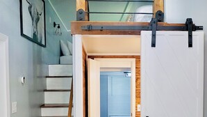 Una escalera conduce a una zona superior con techo de vigas de madera.