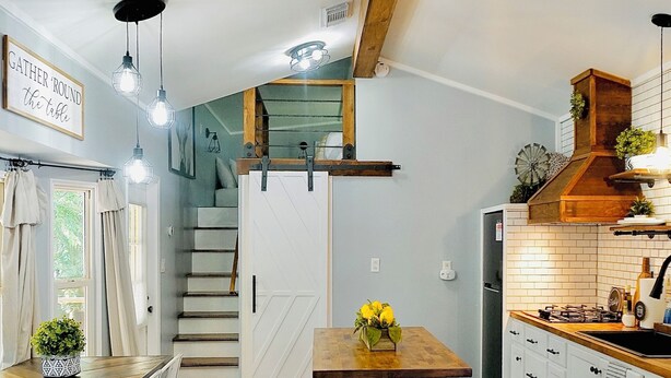 Una cocina moderna con armarios blancos, una isla de madera y un ventilador de techo.