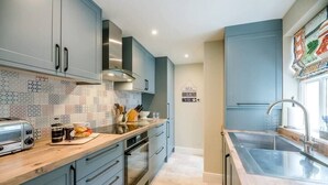 A modern kitchen with grey cabinets, a tiled backsplash, and stainless steel appliances.