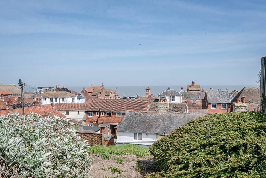A coastal town with terracotta-roofed houses, a clear sky, and a view of the sea.