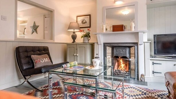A living room with a fireplace, a glass coffee table, a sofa, and a television.