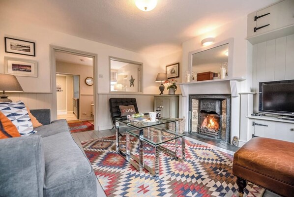 A living room with a fireplace, a sofa, a coffee table, and a television.