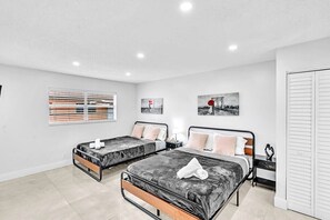 Un dormitorio moderno con dos camas, una ventana con persianas y una obra de arte en la pared.