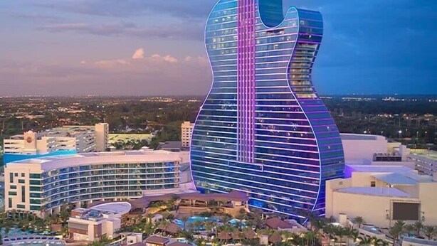 Um resort com um edifício em formato de guitarra, várias piscinas e diversos edifícios de resort.