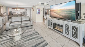 Una sala de estar moderna con un sofá gris, una mesa de centro de vidrio y un televisor de pantalla plana grande.