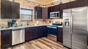 A modern kitchen with dark wooden cabinets, stainless steel appliances, and a granite countertop. - 1 Min to Parkway|4 King BRs|Hot Tub|Pool|Dogs (Pigeon Forge)