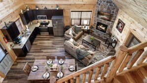 A spacious log cabin interior with a kitchen, dining area, and living room. - 1 Min to Parkway|4 King BRs|Hot Tub|Pool|Dogs (Pigeon Forge)