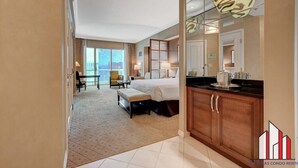 A hotel room with a large bed, a desk, a chair, a sofa, and a view of the city. - MGM Signature-29-617 Penthouse Studio F1 w Balcony (Las Vegas)
