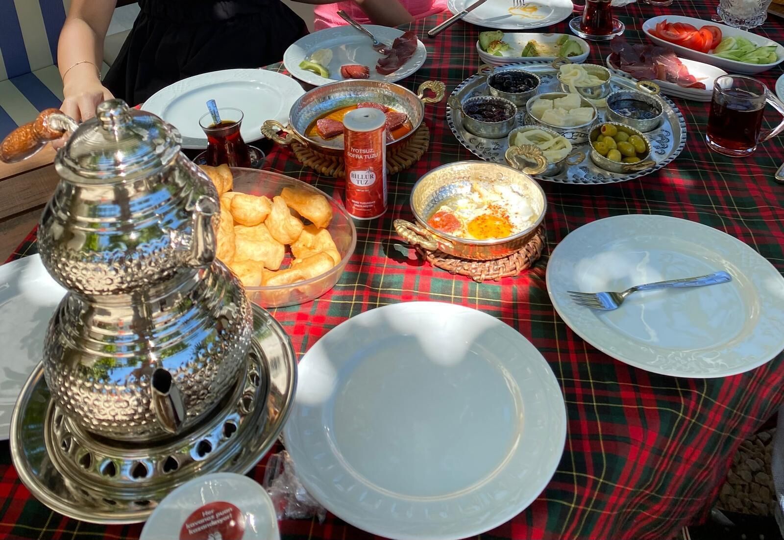 Una mesa dispuesta con diversos platos, incluyendo un samovar, platos y tazones de comida.