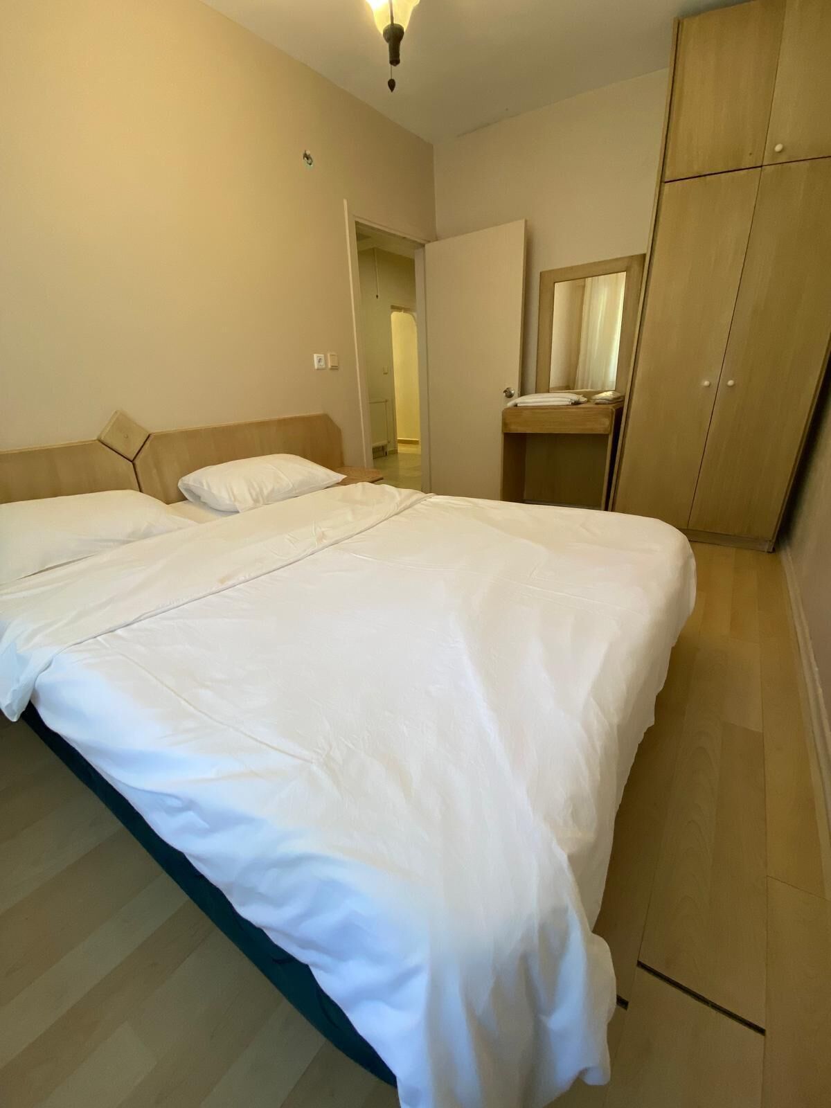 A bedroom with a large bed, a wardrobe, and a mirror.