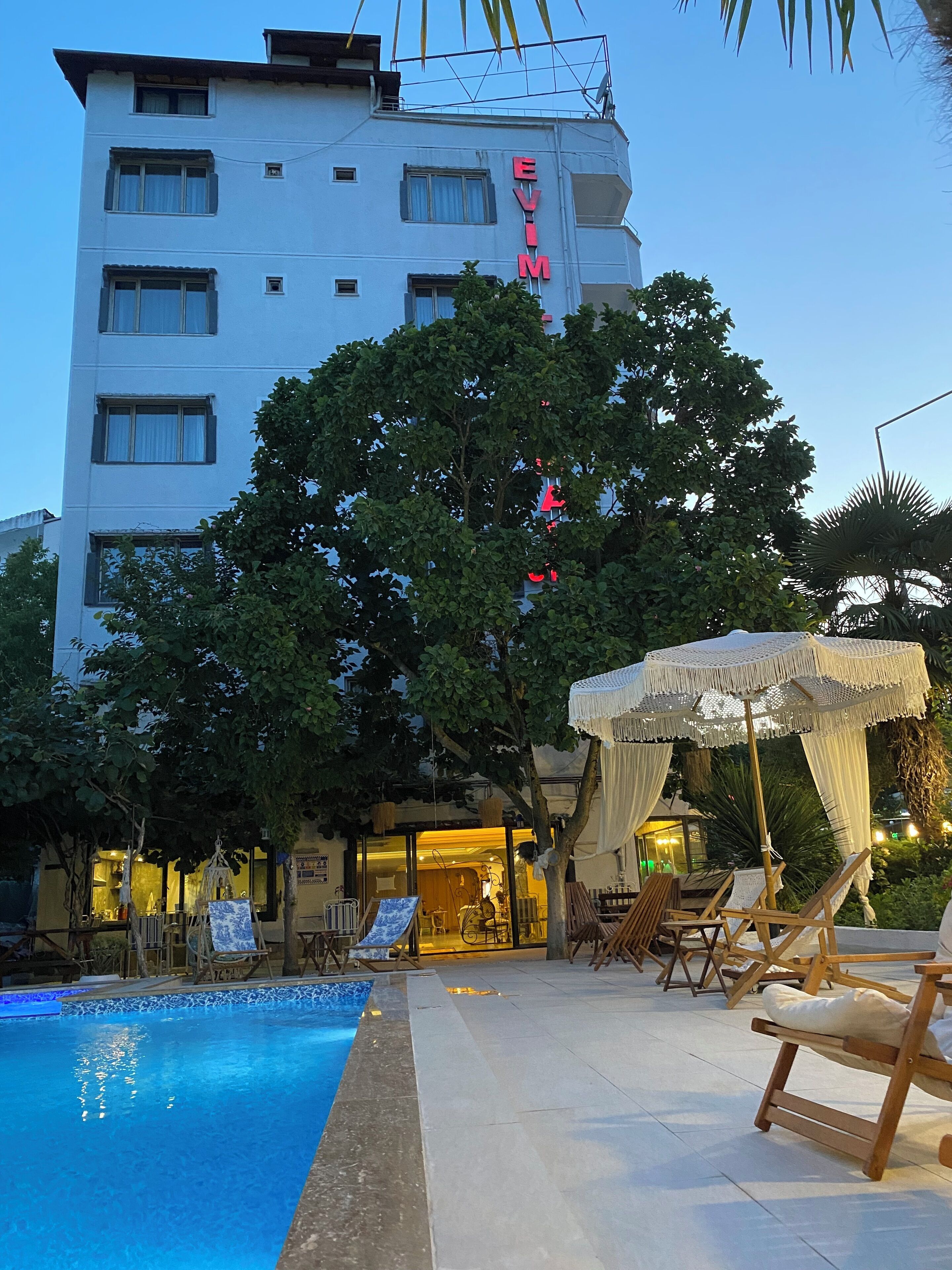 Een hotel met een zwembad, ligbedden en een zonnescherm.