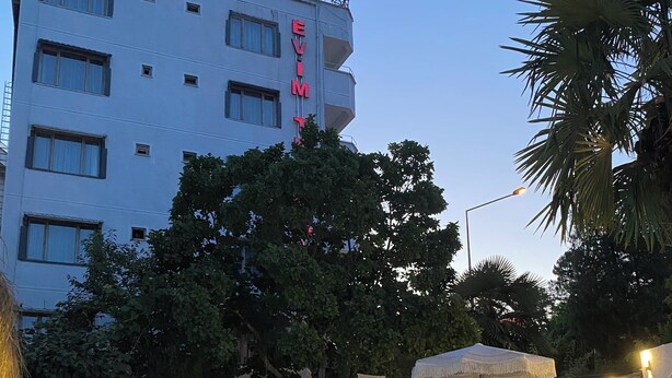 Un hotel con zona de piscina, mobiliario exterior y un edificio con un letrero visible.
