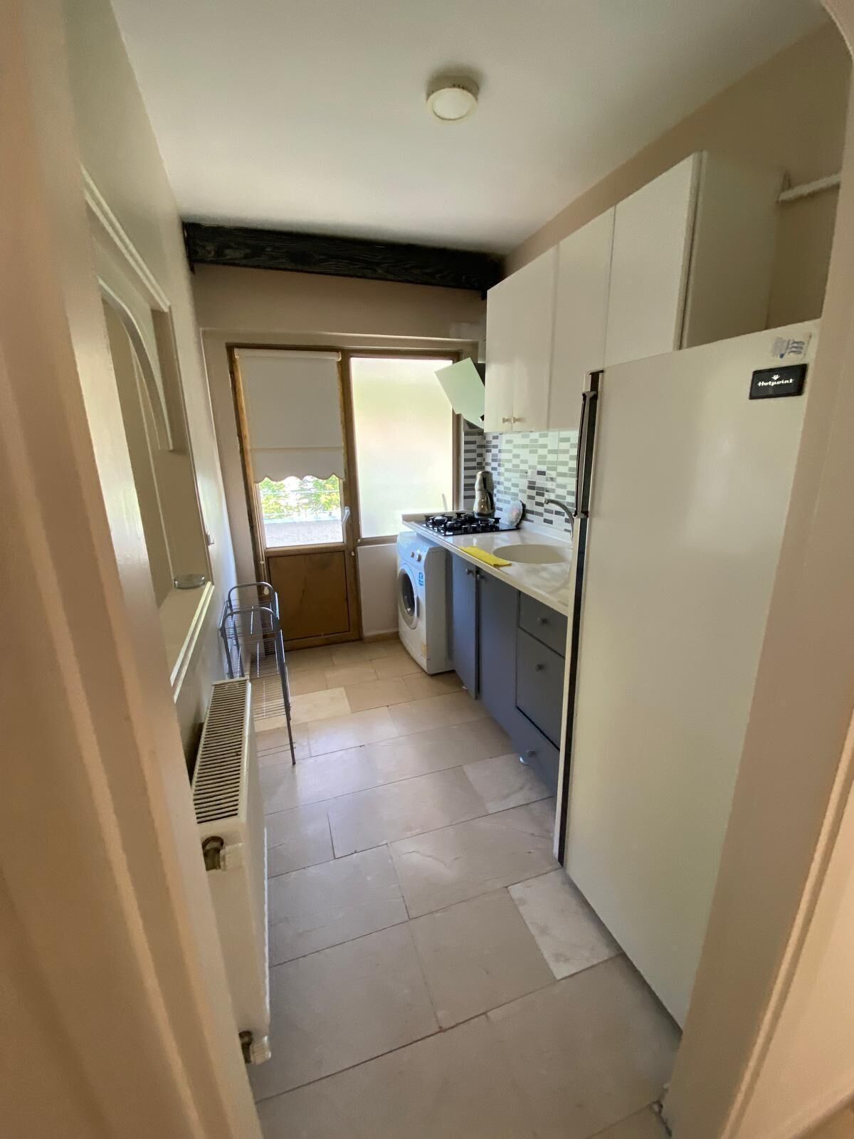 A narrow kitchen with a washing machine, a stove, and a refrigerator.