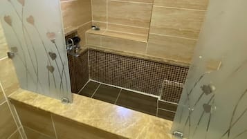 A modern bathroom with a glass partition, a small window, and a tiled floor.