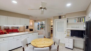 A modern kitchen with white cabinetry, a wooden dining table, and a built-in refrigerator. - Lilly's Pad 3 bedrooms, 3.5 bathrooms (Jekyll Island)