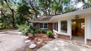 A single-story house with a brick exterior, large windows, and a covered porch. - Lilly's Pad 3 bedrooms, 3.5 bathrooms (Jekyll Island)
