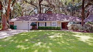 A single-story house with a brick chimney, a front porch, and a well-maintained lawn. - Lilly's Pad 3 bedrooms, 3.5 bathrooms (Jekyll Island)