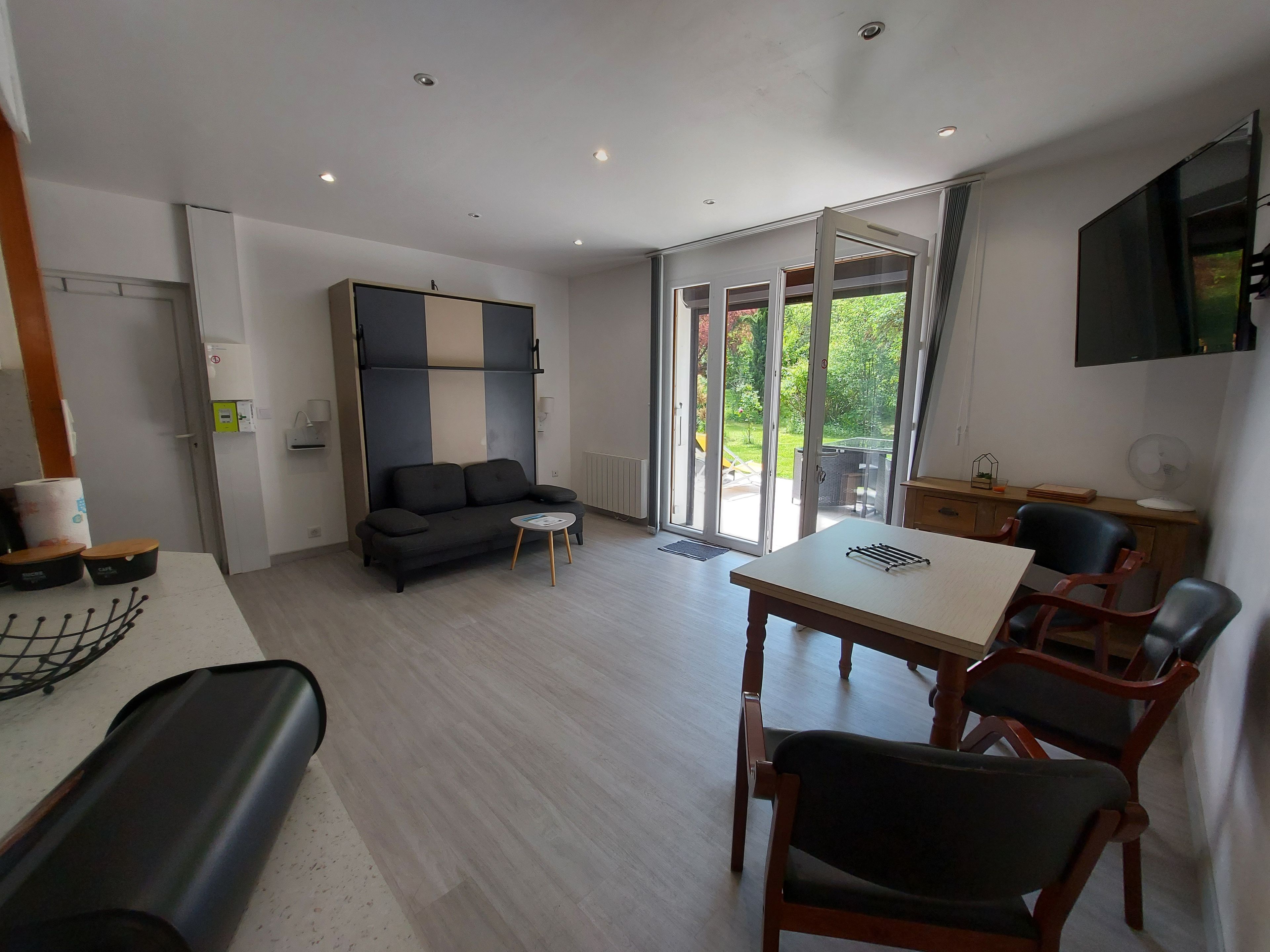 Een moderne woonkamer met een bank, een bijzettafeltje en een eethoek met stoelen.