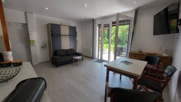 Een moderne woonkamer met een bank, een bijzettafeltje en een eethoek met stoelen.