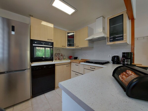 A modern kitchen with stainless steel appliances, wooden cabinets, and a countertop with a bread loaf.