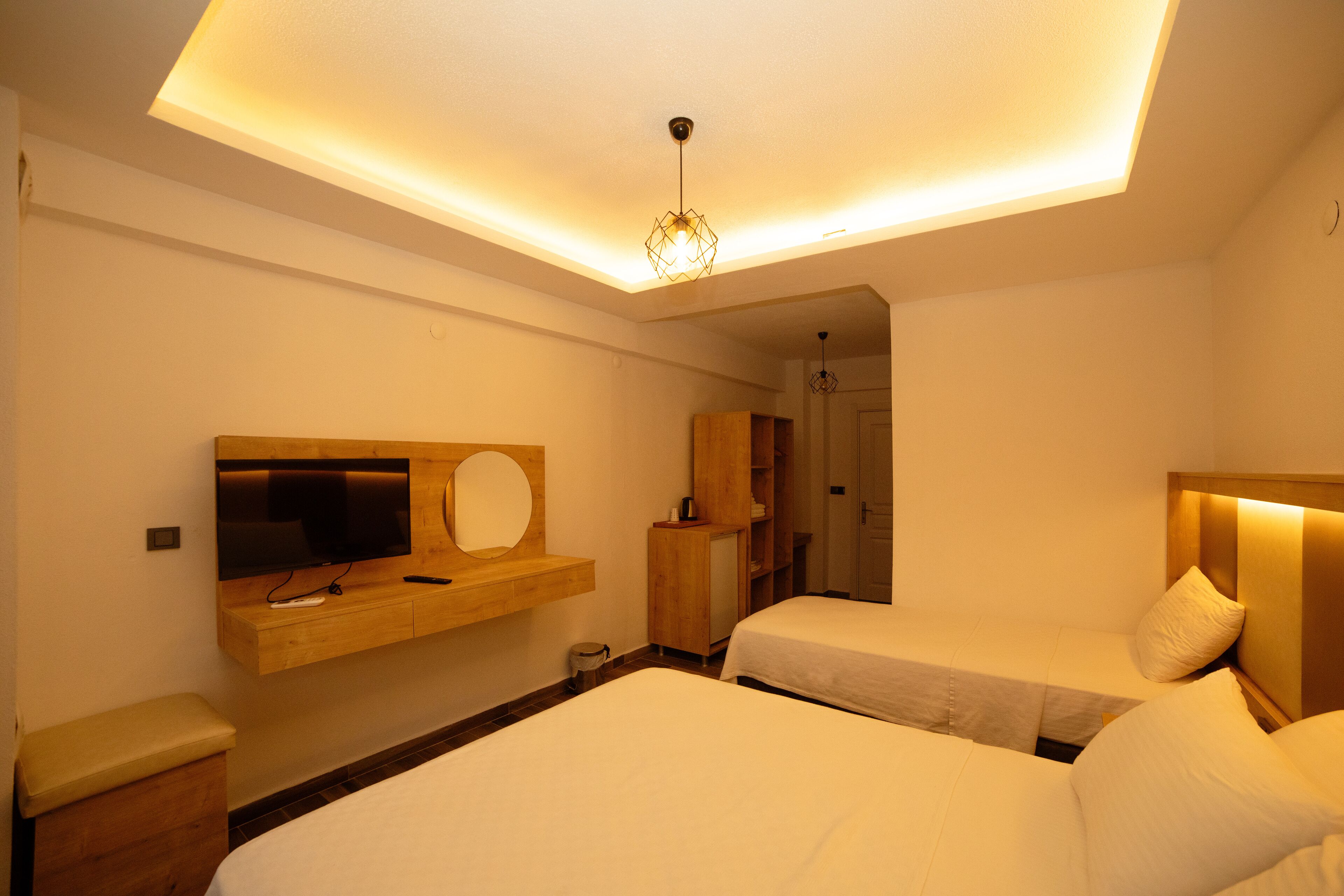 A hotel room with two beds, a TV, a wooden cabinet, and a ceiling light fixture.