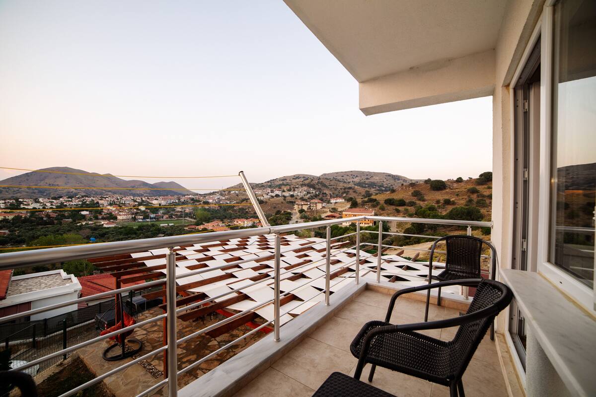 A balcony with a view of a town and mountains.