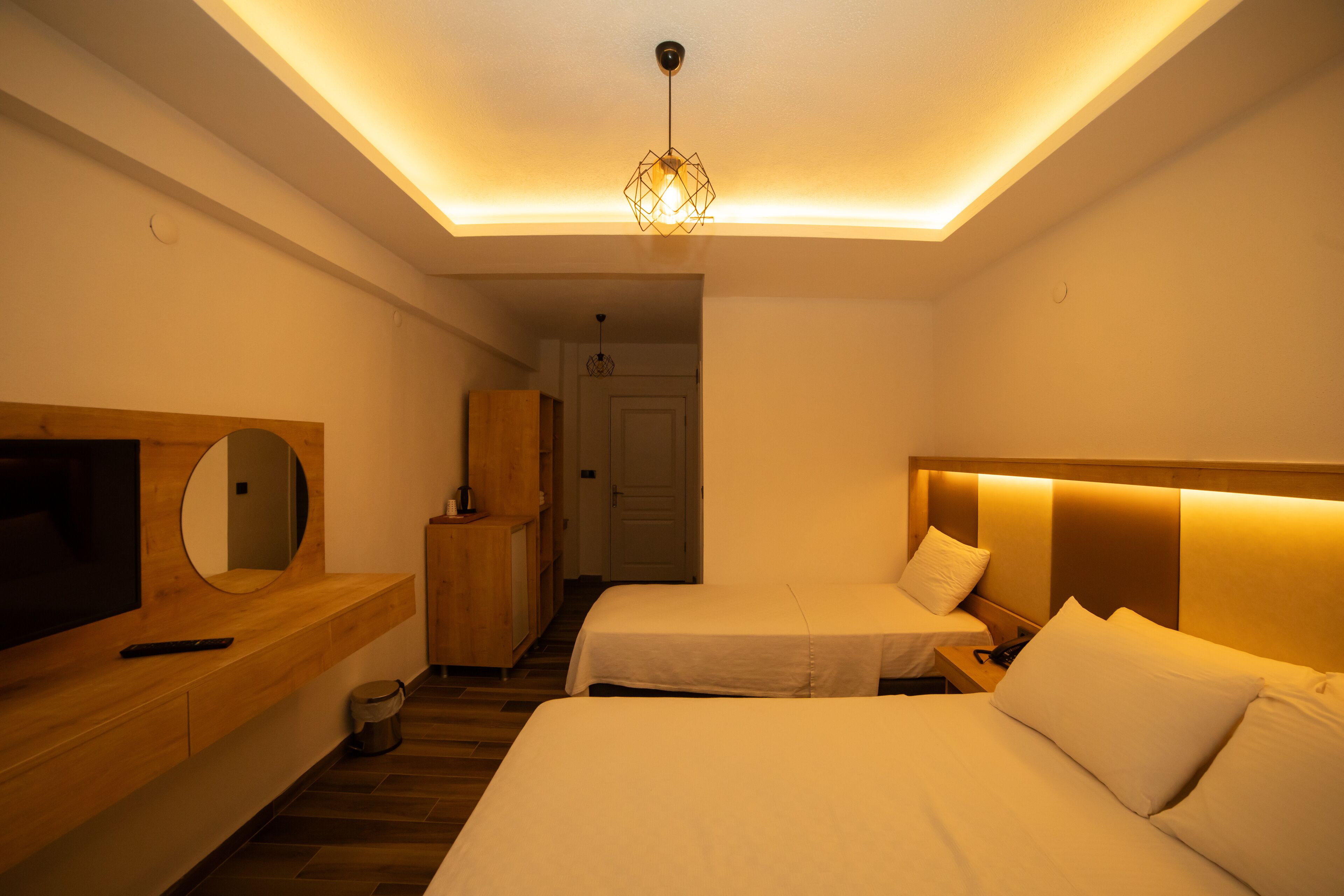 A hotel room with two beds, a TV, a mirror, and a wooden dresser.