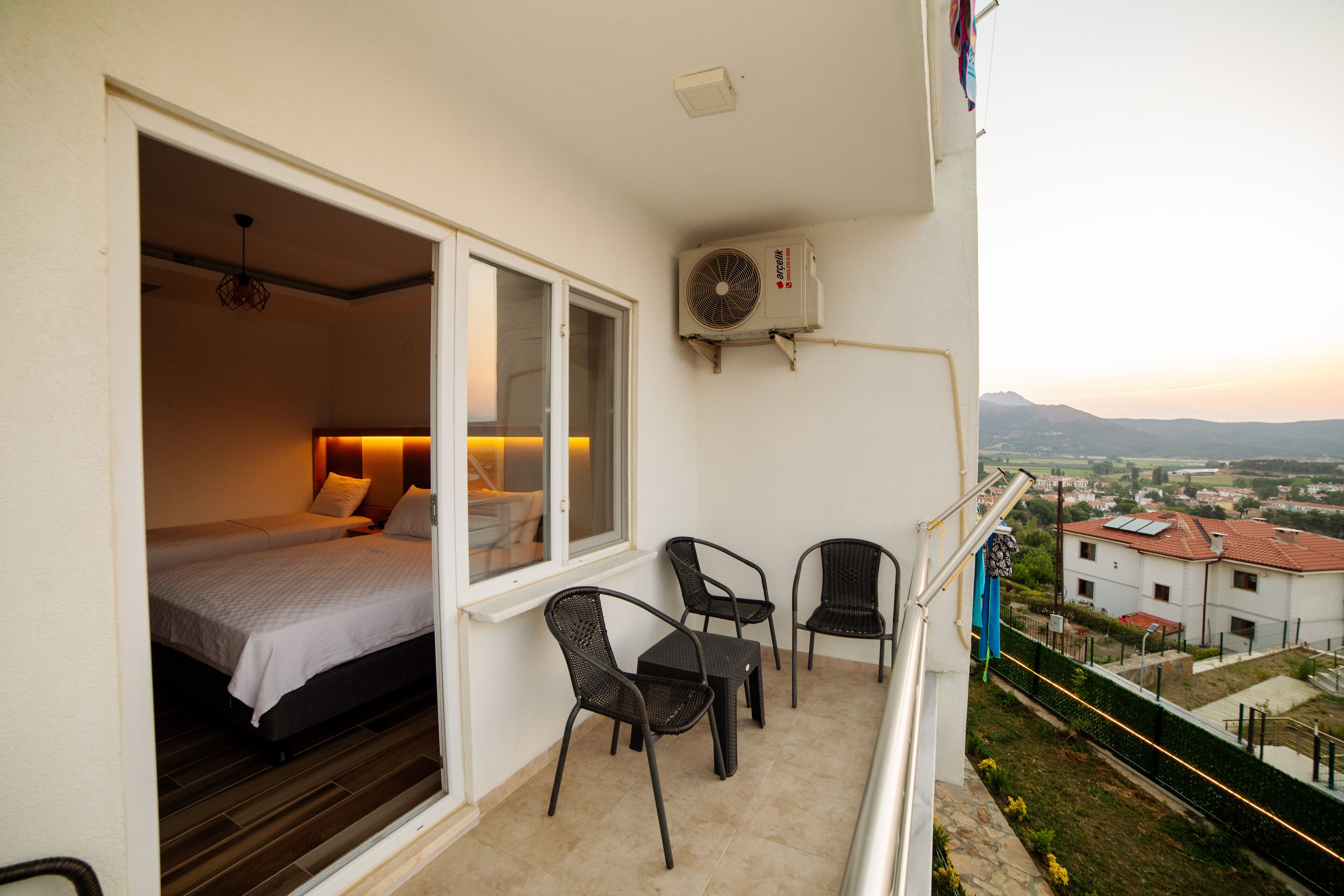 A balcony with a bed, two chairs, and a table.