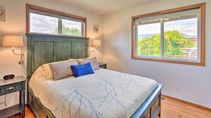 A bedroom with a bed, two bedside lamps, a nightstand, and a window with a view of trees and mountains. - 51 Mi to Mt Rainier: Mtn-View Escape on 8 Acres! (Randle)